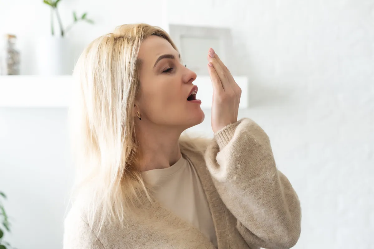 Femme vérifie son haleine avec la main.