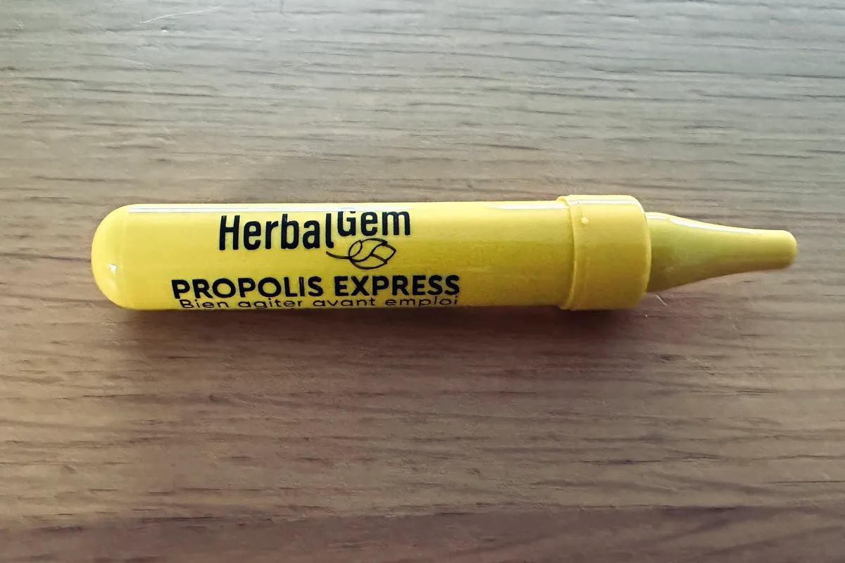 Un shot de Propolis Express de HerbalGem, unidose jaune de 10 ml, posée sur une table en bois